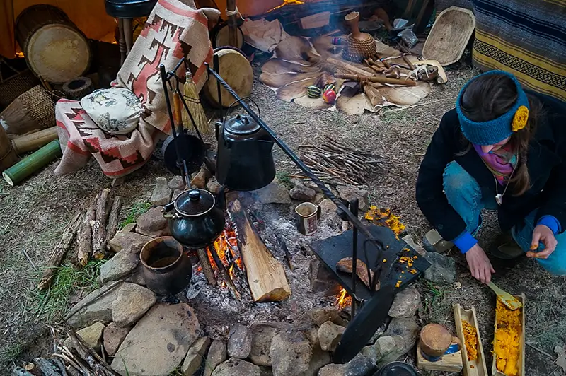 woman cooking sweet potatoes on a primitive fire