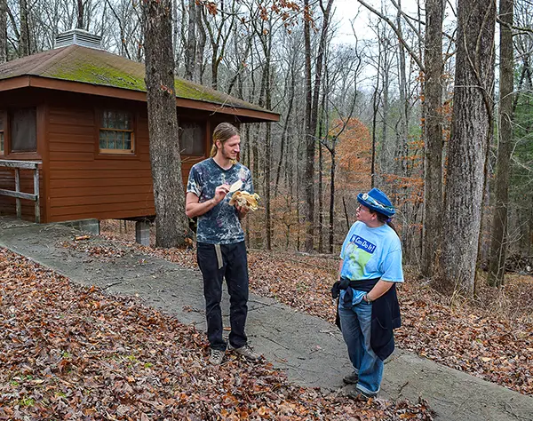 two people standing on a paved path to a cabin