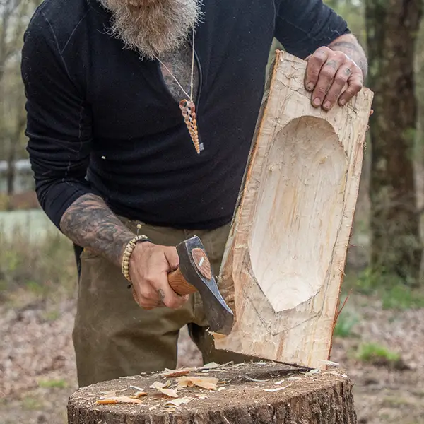 Man cutting a wood bowl with a hatchet