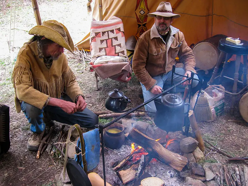 two men cooking in a primitive kitchen