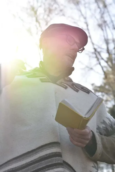man reading from a book with his back to the sun