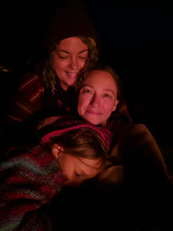 woman and kids cuddling in front of a fire